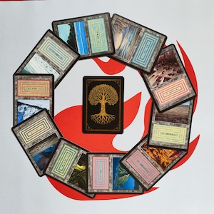 May include: A collection of rectangular trading cards arranged in a circular pattern, featuring landscape images and text. A central card displays a golden tree design on a black background. The cards are set against a white surface with a red flame-like design.