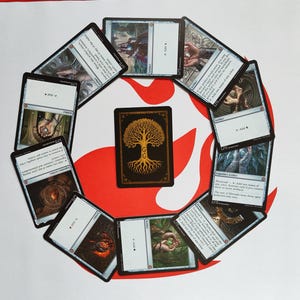 Peut inclure: Un ensemble de cartes à collectionner Magic: The Gathering disposées en cercle. Les cartes présentent diverses illustrations fantastiques et du texte, avec une carte centrale affichant un motif d'arbre doré sur fond noir.