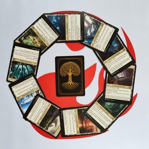 Puede incluir: Un conjunto de cartas coleccionables de Magic: The Gathering dispuestas en círculo alrededor de una carta central. Las cartas presentan paisajes fantásticos y texto. La carta central tiene un diseño de árbol dorado sobre fondo negro.