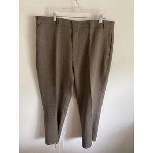 May include: Brown trousers hanging on a clear plastic hanger. The pants have a classic, straight-leg design and a neutral, earthy tone. The trousers are made of a woven fabric and appear to be a standard size.