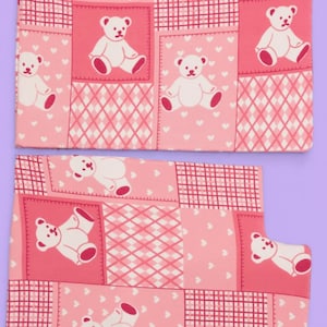Puede incluir: Dos piezas de tela rectangulares con un patr&oacute;n de patchwork rosa. El dise&ntilde;o incluye cuadrados alternos de ositos de peluche blancos sobre fondo rosa, peque&ntilde;os corazones blancos sobre fondo rosa y un patr&oacute;n de cuadr&iacute;cula a cuadros.