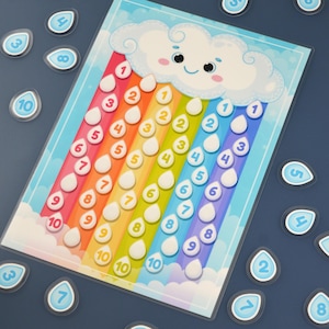 May include: A colorful educational toy featuring a smiling cloud and rainbow-colored raindrops with numbers 1-10. Includes separate raindrop-shaped number tiles. The background is a light blue, creating a playful learning environment.