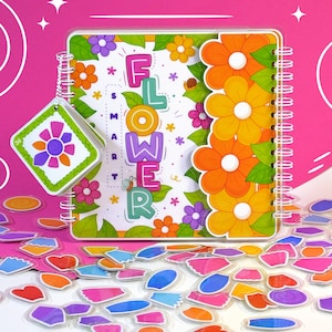 以下が含まれることがあります： カラフルな文字で「FLOWER」と書かれたスパイラル綴じのノート。花のイラストで囲まれています。お揃いのタグと様々な花型のステッカーが散りばめられています。ノートとタグは、明るい色使いの花柄デザインです。