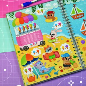 May include: A spiral-bound activity book with a beach theme. The illustrations include an ice cream truck, cartoon animals, and ice cream cones. A blue and white marker rests on the top. The text reads "On this hot and sunny day..."