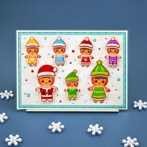 May include: A collection of gingerbread people stickers in various outfits, including Santa hats and elf hats. The stickers are on a white background with a light blue border and snowflake accents. The gingerbread people have smiling faces and are in different colors.