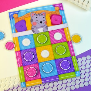 May include: A colorful children's game board featuring a cartoon cat in bed. The board has a grid of squares in various colors with circular game pieces. The game pieces are pink, yellow, and blue. The game is designed for children.