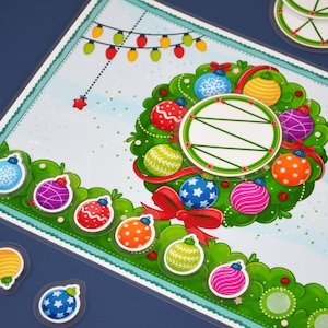May include: A festive Christmas-themed illustration featuring a wreath adorned with colorful ornaments and a red bow. A string of lights and star add to the holiday cheer. Additional ornament stickers are scattered around the wreath.