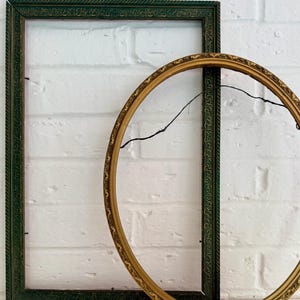 May include: A rectangular dark green picture frame with a textured gold inner border and a circular gold picture frame with an ornate, embossed pattern. The circular frame features a thin black wire attached to the back for hanging purposes.