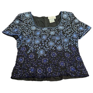 May include: Black short-sleeved top with a square neckline, adorned with intricate blue floral and leaf embroidery. The design features a gradient effect, transitioning from dark to light blue. The top has a zipper closure in the back.