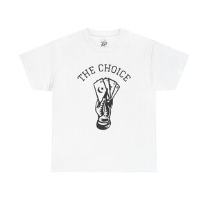 Peut inclure: T-shirt blanc avec un motif noir d'une main tenant des cartes à jouer, dont une avec un croissant de lune et une étoile. Le texte "THE CHOICE" est arqué au-dessus des cartes.