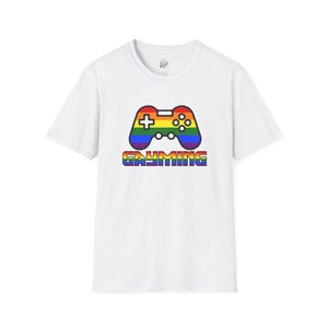 Puede incluir: Camiseta blanca con un diseño de mando de videojuegos en arcoíris y la palabra "GAYMING" en colores arcoíris. El diseño del mando incluye una cruz, botones y un joystick.