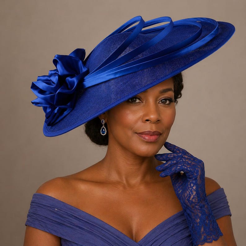 Peut inclure: Un chapeau bleu roi &agrave; large bord orn&eacute; de rubans d&eacute;coratifs. Le chapeau est orn&eacute; d'une grande fleur en tissu. La femme porte une robe bleue assortie et des gants en dentelle. Un accessoire de mode pour les &eacute;v&eacute;nements.