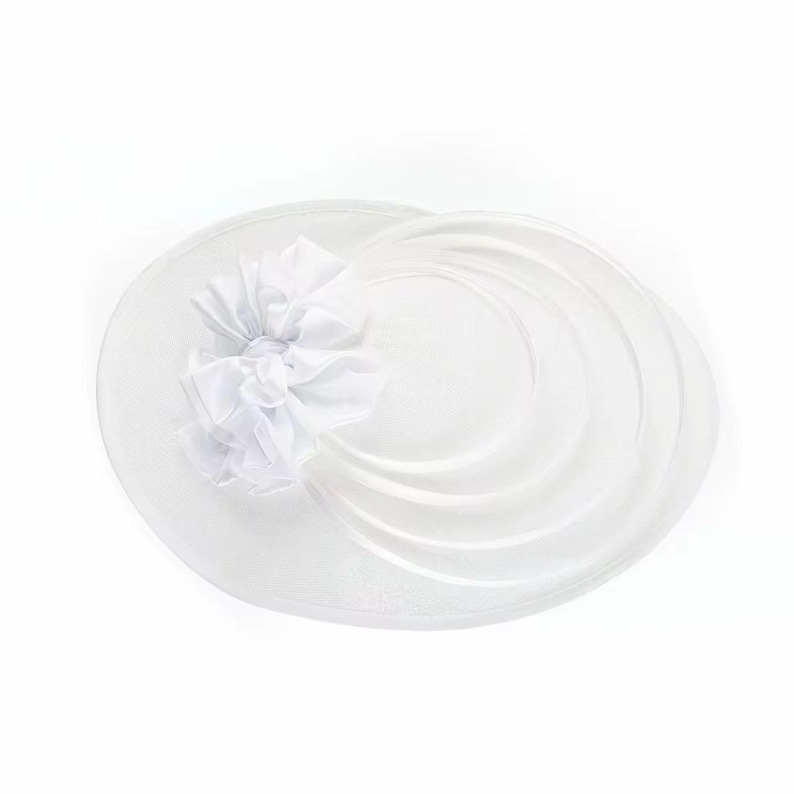 Peut inclure: Chapeau blanc &agrave; large bord orn&eacute; d'une fleur d&eacute;corative en tissu superpos&eacute;. Le chapeau pr&eacute;sente un design circulaire avec un voile ondul&eacute; transparent, cr&eacute;ant un look &eacute;l&eacute;gant. Id&eacute;al pour les occasions sp&eacute;ciales.