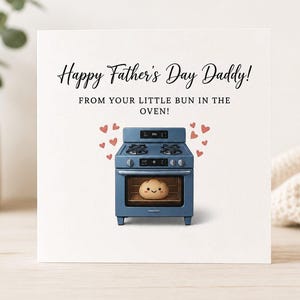 May include: A Father's Day card with a blue oven illustration and the text "Happy Father's Day Daddy! From your little bun in the oven!" The oven has a smiling bun inside, surrounded by red hearts.