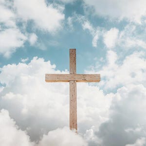 May include: A wooden cross against a backdrop of a bright blue sky and fluffy white clouds. The cross is made of light-colored wood and is centered in the frame, with the clouds surrounding it.