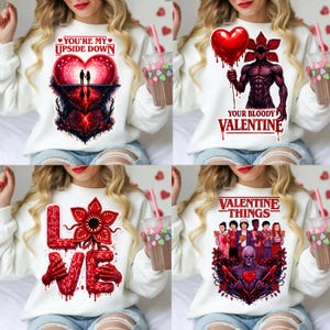 Puede incluir: Sudaderas blancas con diseños temáticos de San Valentín. Los diseños incluyen un corazón con siluetas, un Demogorgon sosteniendo un globo de corazón, la palabra "LOVE" con una flor Demogorgon y un grupo de personajes con el texto "VALENTINE THINGS".