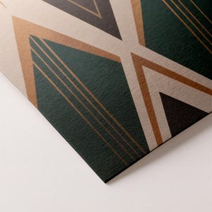 May include: Close-up of a geometric design with a textured surface. The design features dark green, tan, and bronze-colored shapes, including triangles and lines. The artwork has a modern, art deco style.