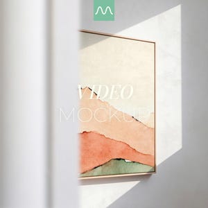 May include: A framed art print featuring a watercolor landscape in shades of peach, coral, and green. The artwork is displayed on a white wall, with the words "VIDEO MOCKUP" overlaid on the image. The frame is a light wood color.