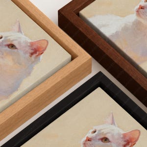 May include: Three framed canvas prints featuring a white cat portrait. The set includes one light wood frame, one dark wood frame, and one black frame. Each canvas displays a close-up painting of a white cat with visible brushstroke textures.