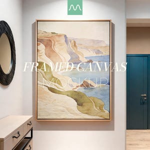 Puede incluir: Un lienzo enmarcado que muestra un paisaje estilo acuarela con acantilados costeros, orillas arenosas y agua azul. La obra de arte se presenta en un marco de madera clara con el texto blanco FRAMED CANVAS MOCKUP superpuesto en el centro.