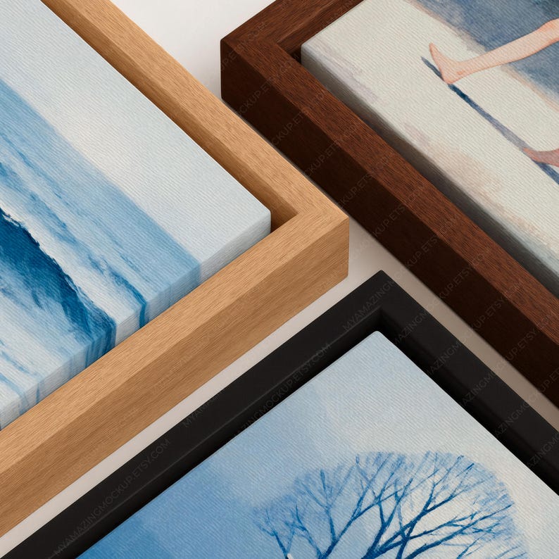 May include: Three rectangular canvas prints in floating frames. One frame is light wood with a blue ocean wave print, one is dark wood with a beach scene, and one is black with a blue tree silhouette print. Each canvas has a visible fabric texture.