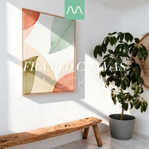 May include: A framed canvas mockup featuring an abstract watercolor design with orange, green, and beige shapes. The artwork is displayed on a white wall, with a wooden bench and a potted plant in the foreground. The text "FRAMED CANVAS MOCKUP" is visible on the canvas.