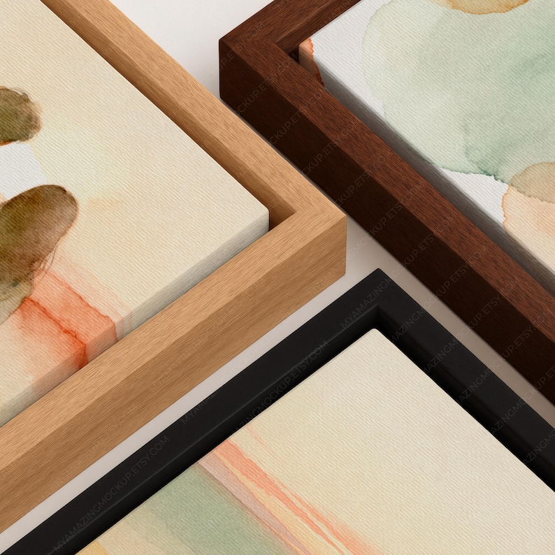 May include: Three rectangular canvas prints featuring abstract watercolor designs in shades of sage green, soft orange, and cream. Each canvas is encased in a distinct floating frame, with one light wood, one dark wood, and one black frame finish.