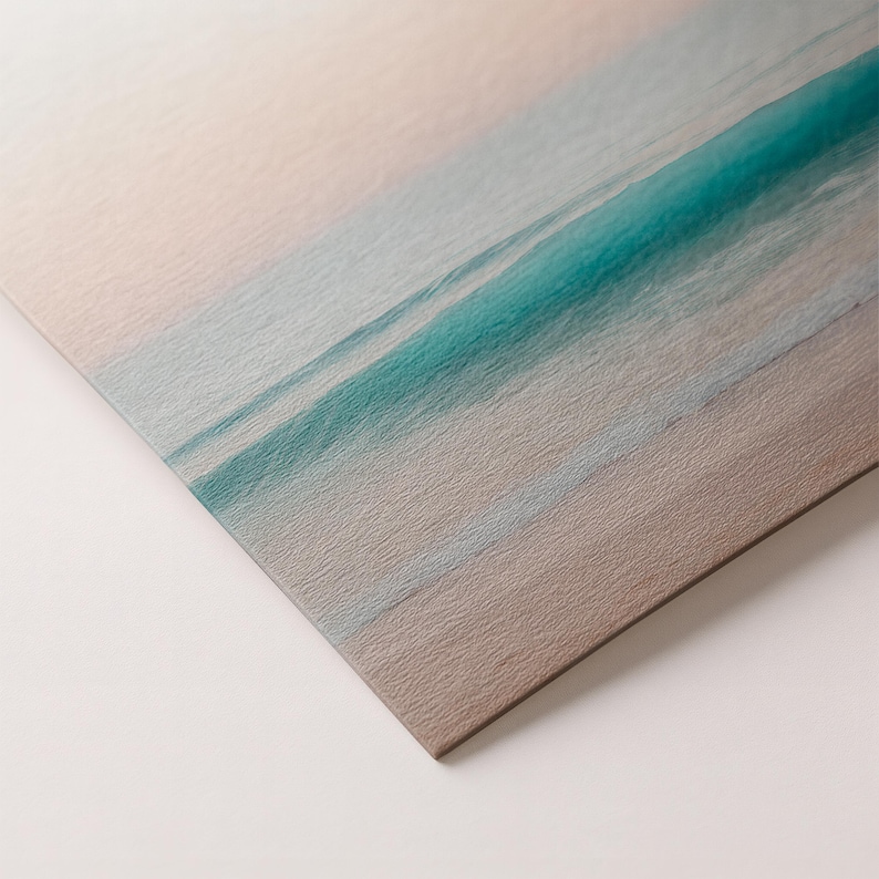 May include: A print of a beach scene with a turquoise wave breaking on the shore. The sky is a soft pink and the sand is a light brown. The print has a textured surface.