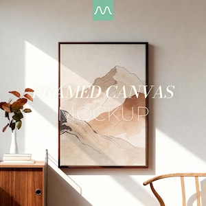 Puede incluir: Un lienzo enmarcado vertical que muestra un paisaje de montaña abstracto en tonos beige, bronceado y marrón con detalles de líneas negras finas. El texto FRAMED CANVAS MOCKUP está superpuesto en blanco. Un pequeño logotipo turquesa está arriba.
