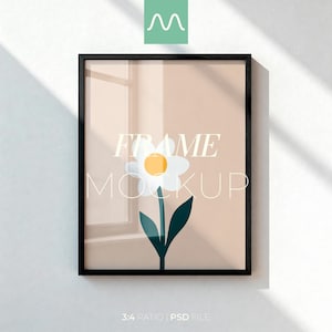 May include: A black rectangular frame containing a print of a single white flower with a yellow center and dark green leaves on a light beige background. The text "FRAME MOCKUP" is overlaid in white across the center of the artwork.