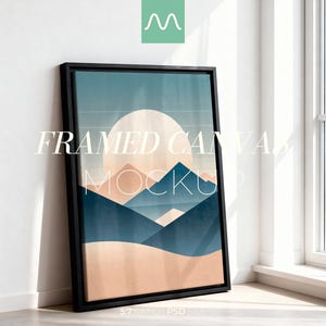 Puede incluir: Una maqueta de lienzo enmarcado con un diseño de paisaje. La obra de arte presenta un gran sol y montañas en tonos azules, melocotón y beige. El lienzo está en un marco negro y se apoya contra una pared blanca. El texto en el lienzo dice "FRAMED CANVAS MOCKUP".