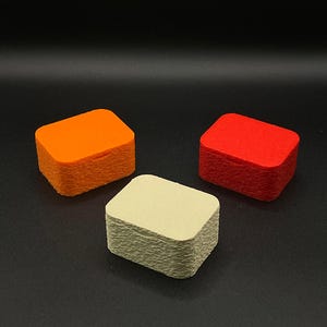 Könnte beinhalten: Drei Stapel kleiner, rechteckiger Karten mit abgerundeten Ecken. Ein Stapel ist orange, ein anderer rot und der dritte ist hellbeige. Die Karten sind ordentlich vor einem schwarzen Hintergrund gestapelt.