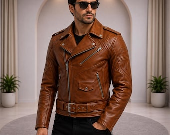 Puede incluir: Una chaqueta de cuero color canela para motocicleta con cuello ancho de muesca, cremalleras de metal plateado, un cinturón con hebilla en la parte delantera y detalles acolchados en los hombros. Se lleva sobre una camisa negra y pantalón negro.