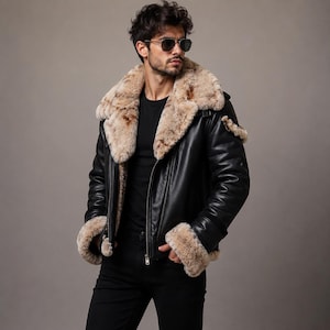 Puede incluir: Una chaqueta de cuero negro con un cuello ancho de piel sintética de color tostado y puños a juego. La chaqueta tiene un cierre de cremallera frontal, mangas largas y un forro de piel visible a lo largo de los bordes, sobre una camiseta negra.