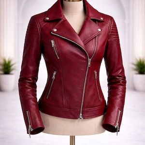 May include: A deep red leather jacket featuring an asymmetrical silver-tone zipper closure, a notched lapel with silver snaps, zippered pockets on the chest and sides, and quilted detailing on the shoulders and sleeve cuffs.