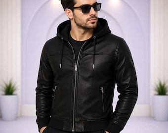 May include: A black hooded jacket featuring a smooth finish, a full-length front zipper, and two side pockets with silver-toned zippers. The garment includes a drawstring hood with metal aglets and ribbed cuffs at the sleeves and waist hem.