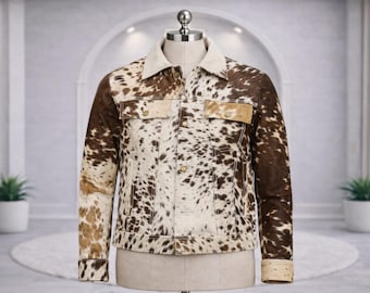 May include: A jacket featuring a brown and white cowhide print pattern, a light-colored collar, long sleeves with buttoned cuffs, two chest pockets with flaps, and a front button closure, displayed on a mannequin torso.