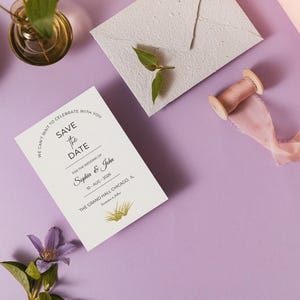 **Alt Text:**
Elegant save the date wedding invitation card styled on a pastel lavender background with handmade envelope, silk ribbon, floral accents, and modern wedding stationery, perfect for romantic wedding announcements and bridal event planning.