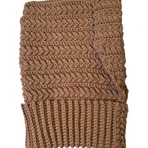 May include: A brown, handmade crochet hat with a textured, woven pattern. The hat features a ribbed brim and a folded-over cuff. The hat is made of a soft, warm yarn.