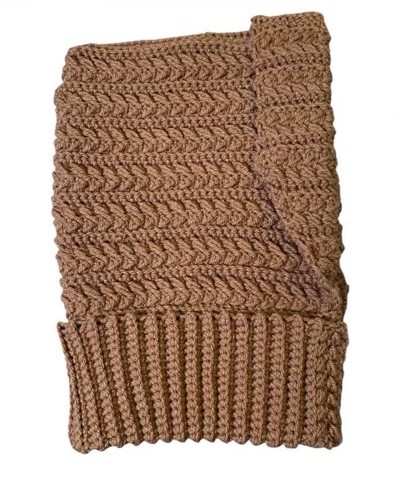 May include: A brown, handmade crochet hat with a textured, woven pattern. The hat features a ribbed brim and a folded-over cuff. The hat is made of a soft, warm yarn.