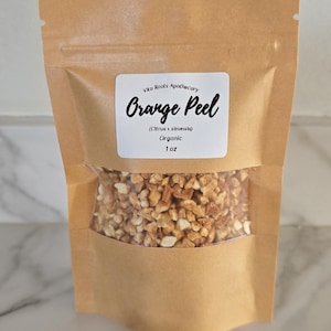 May include: A kraft paper bag with a clear window, filled with dried orange peel. The label reads "Vita Roots Apothecary Orange Peel (Citrus x sinensis) Organic 1 oz."