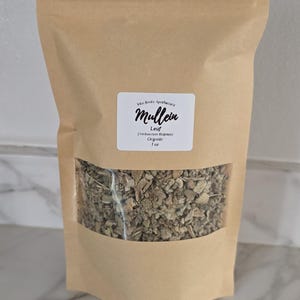 May include: A tan, resealable kraft paper pouch containing dried mullein leaf. A white label on the front reads: Vita Roots Apothecary, Mullein, Leaf (Verbascum thapsus), Organic, 1 oz. A clear rectangular window reveals the dried green herbs inside.