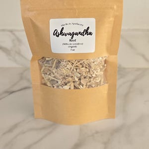 May include: A brown paper bag with a clear window, filled with dried ashwagandha root. The label reads "Ashwagandha Root" and includes the brand name "Vita Roots Apothecary", the botanical name, and the weight, 1 oz.