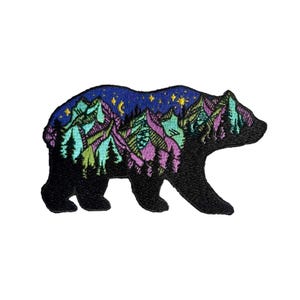 May include: Embroidered patch featuring a black bear silhouette with a mountain and starry night design. The mountains are in shades of green, purple, and blue, with yellow stars and a crescent moon against a dark blue sky. This patch is ideal for jackets, bags, or other fabric items.