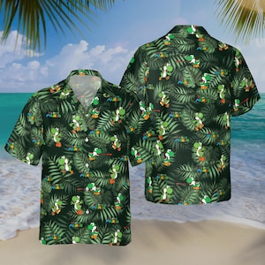 May include: A short-sleeved button-down shirt featuring a repeating pattern of the character Yoshi from Super Mario, set against a backdrop of green tropical leaves. The words "SUPER MARIO" are also visible on the shirt.