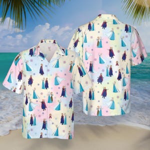 May include: Two short-sleeved button-down shirts with a colorful pattern. The shirts feature a repeating design of cartoon characters in blue, purple, and pink dresses, with snowflakes on a pastel rainbow background. The shirts are likely made of a lightweight fabric.