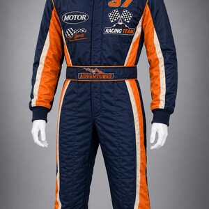 May include: A navy blue and orange racing suit featuring the number 37, checkered flag graphics, and patches reading MOTOR, RACING TEAM, and ADVENTURES. The suit has a high collar, long sleeves with orange side panels, and a matching waist belt.