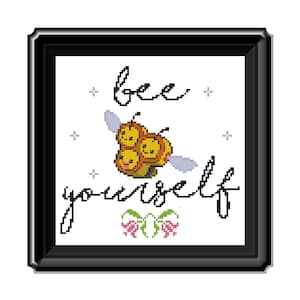 May include: A cross-stitch pattern with a cute cartoon bee and the text "bee yourself". The bee is yellow and black with three faces. The text is in black cursive font. There are small white stars and pink flowers in the background.