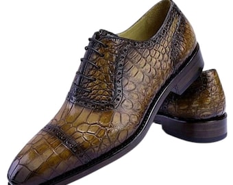 Puede incluir: Un par de zapatos de vestir de cuero marrón con un patrón texturizado similar al de un cocodrilo. Los zapatos tienen un diseño Oxford clásico con cordones y un acabado pulido. Las suelas y los tacones son de color marrón oscuro.