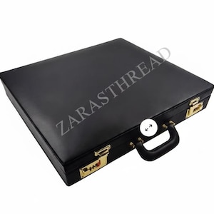 May include: A black briefcase with gold combination locks and fittings. The briefcase has a black handle and the text "ZARASTHREAD" is printed on the top.